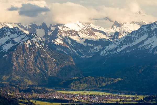 Úžasný výhled Sněhem pokryté hory s vesnicí v údolí. Západ slunce nebo východ slunce v Oberstdorfu, Německo. — Stock fotografie