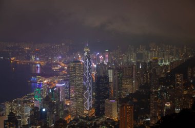 Geceleri yanıp sönen ışıkları olan Hong Kong binalarının manzarası.