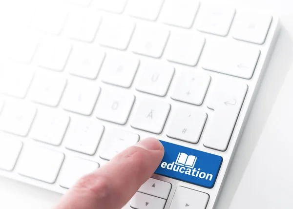 Vinger te drukken een blauw label onderwijs met boek-symbool op een computer toetsenbord concept — Stockfoto