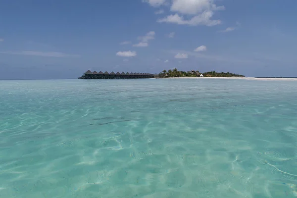 Тропические Мальдивы остров с пальмами и водными домиками видели с песчаного берега в бирюзовой воде — стоковое фото