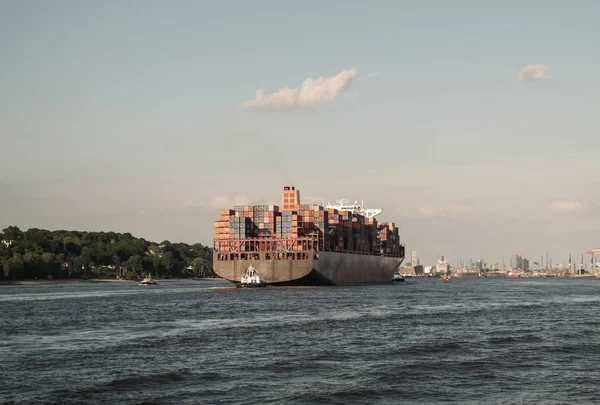 Grande navio contêiner na água com docas portuárias no fundo sob o céu azul em Hamburgo, Alemanha — Fotografia de Stock