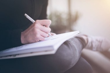 yazma veya bacaklarını üzerinde dinlenme bir not defteri üzerinde karalama kadın