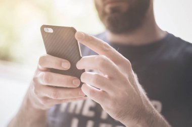 genç adam güneş ışığı manifatura smartphone cep telefonu ile ayakta 