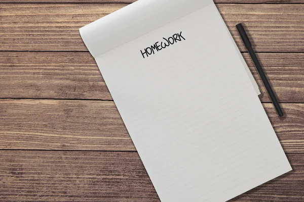 Draufsicht auf blanko linierten Notizblock mit Wort-Hausaufgaben und Stift nebeneinander auf rustikalem Holztisch-Hintergrund-Vorlage — Stockfoto