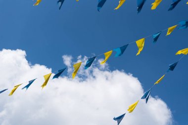 mavi ve sarı kiraz kuşu mavi yaz gökyüzüne karşı lunapark Festivali'nde rüzgarda sallayarak ipte bayraklar 