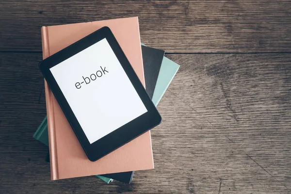 Lector de libros electrónicos en una pila de libros sobre el concepto de mesa de madera rústica — Foto de Stock