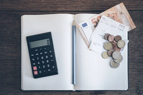 Account boekconcept met contant geld rekeningen en munten, laptop en calculator op rusitc houten tafel — Stockfoto