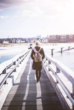 Baltık Denizi, ahşap iskele üzerinde yürüyen sırt çantası ile sarışın kadın