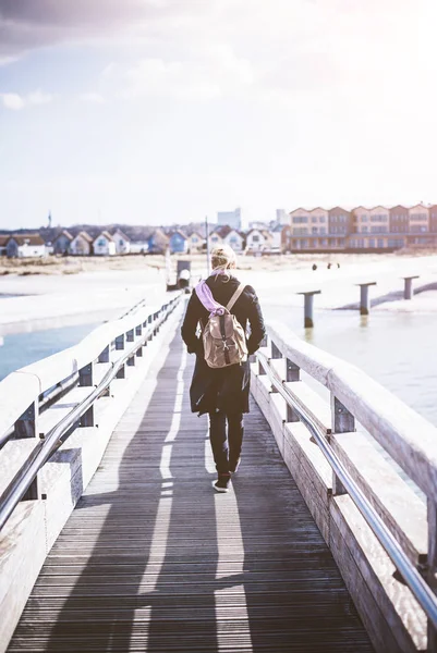 Baltık Denizi, ahşap iskele üzerinde yürüyen sırt çantası ile sarışın kadın