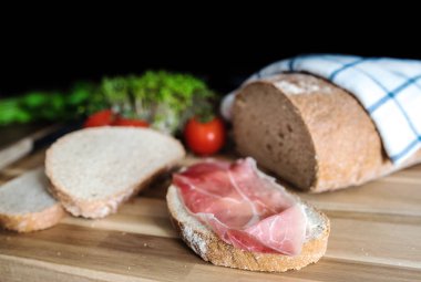 tereyağı ve Ahşap doğrama tahtası üzerinde füme jambon ile dilimlenmiş ekmek
