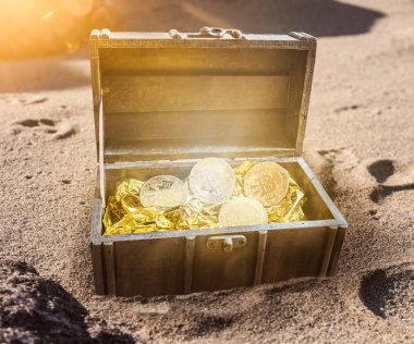 Hazine sandığı dolu altın kızdırma tarafından çevrili bitcoins ile kısmen toprağa verdim kum plaj