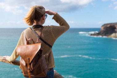 arkadan görünüşü cliff okyanus gözleri elle ışığından koruyucu yukarıda üzerinde duran genç sarışın kadın