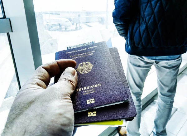 Рука тримає паспорти та посадковий талон біля воріт аеропорту — стокове фото
