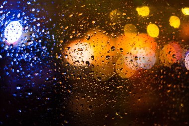 bulanık şehir ve Trafik ışıkları ıslak araba penceresinden görülen
