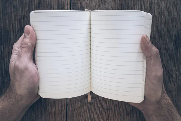 Bovenaanzicht van mannelijke handen met open leeg dagboek op rustieke houten tafel — Stockfoto