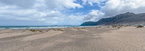 Playa de famara Strand und Bergkette auf Lanzarote, Kanarische Inseln, gegen Meer und Himmel — Stockfoto