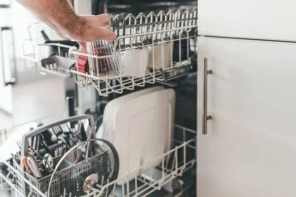 Man loading or emptying dishwasher in kitchen — Stock Photo, Image