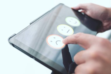 Dijital tablet dokunmatik ekrandaki gülen yüze dokunarak olumsuz geri bildirim yapan kişi