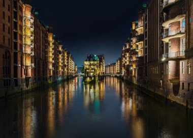 Hamburg 'un Speicherstadt semtindeki eski depo bölgesinde uzun pozlu kanal görüntüsü.