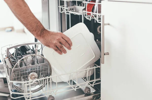 Людина спорожнює або завантажує посудомийну машину на кухні — стокове фото