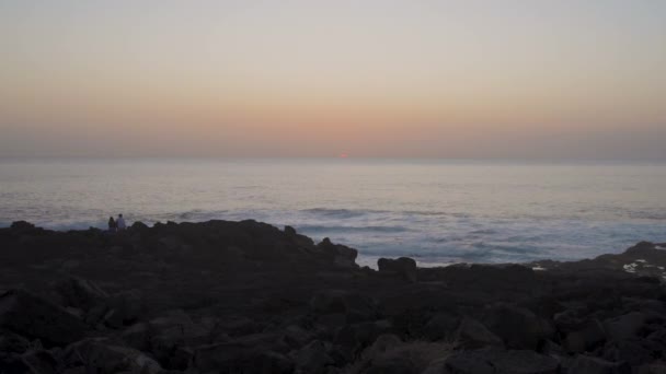 Klippig kust mot hav och gyllene himmel under solnedgången — Stockvideo