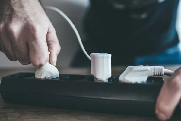 hand plugging power cord into power strip outlet