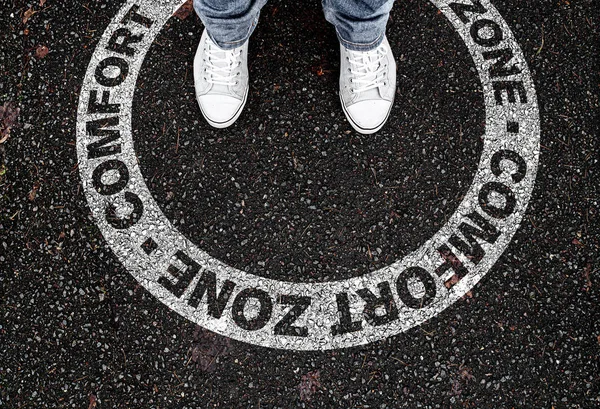 Piernas de la persona de pie en la marca circular en la carretera con texto ZONA DE CONFORT — Foto de Stock