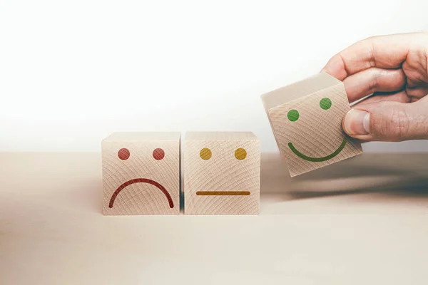 sad, neutral and happy smiling face symbol on wooden blocks