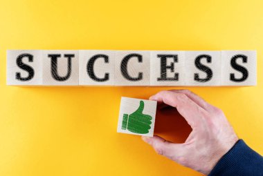word SUCCESS and thumbs up icon on wooden toy blocks