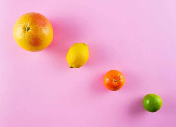 Diretamente acima tiro de frutas cítricas coloridas diferentes no fundo rosa — Fotografia de Stock