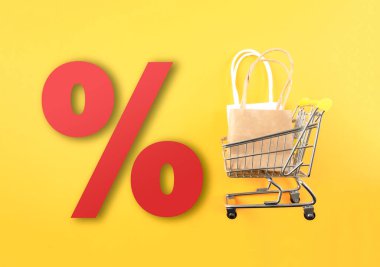 shopping cart with shopping bags and large red percent sign against yellow background