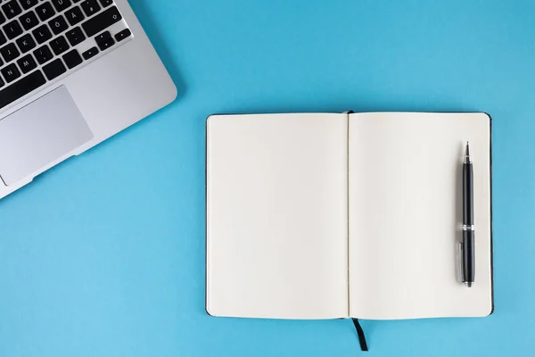Deschide jurnalul sau notebook-ul cu pagini albe goale și laptop-ul pe fundal albastru — Fotografie, imagine de stoc
