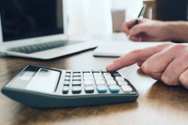 Not alırken cep hesap makinesi kullanan kişinin yakın çekim görüntüsü