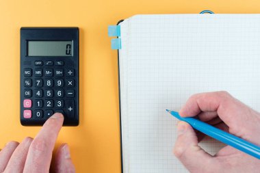 Not alırken cep hesap makinesi kullanan kişinin yakın çekim görüntüsü