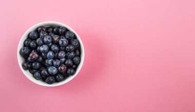 Taze böğürtlenlerle dolu küçük beyaz çömlek kasesinin üstünde.