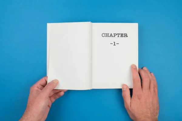 Top view of person fiipping open a book with text CHAPTER 1 on first page — Stock Photo, Image