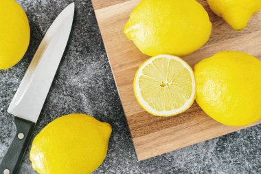 Olgun organik limonlar mutfak tezgahında tahta kesme tahtası ve bıçakla