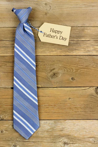 Happy Fathers Day tag with blue striped tie on rustic wood