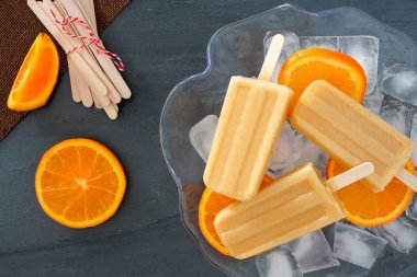 Kayrak karşı bir buz dolu kabın içinde portakal yoğurt popsicles