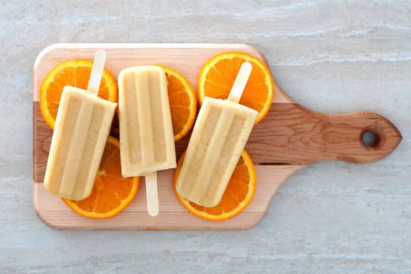 Du yaourt orange avec des tranches de fruits sur une planche à pagaie en bois — Photo
