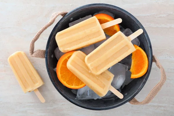Ghiaccioli allo yogurt all'arancia in un secchio pieno di ghiaccio rustico — Foto Stock