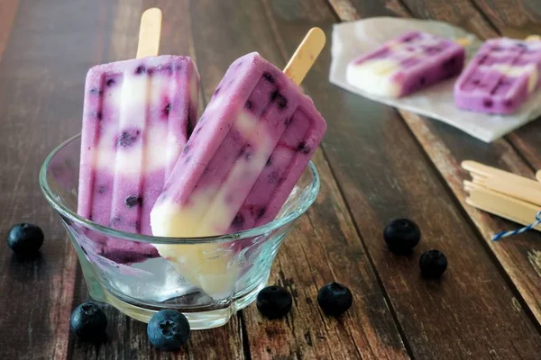 Blåbär vanilj popsicles i en tydlig skål mot rustikt trä — Stockfoto