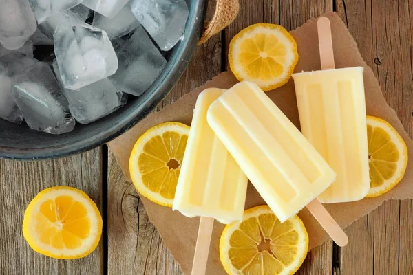 Picolés de iogurte de limão sobre papel com fundo de madeira rústica — Fotografia de Stock