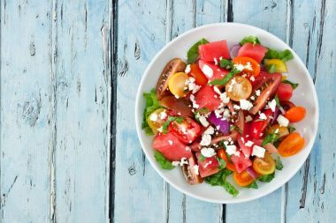 Mavi ahşap üzerine görünümünün üzerinde beyaz peynir karpuz ve domates salatası