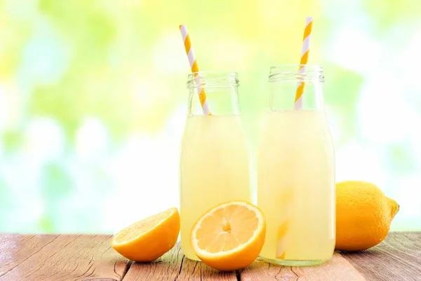 Two bottles of lemonade with de-focused outdoor background — Stock Photo, Image