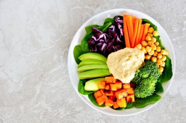 Öğle Yemeği kase sebze ve Humus, mermer üzerinde havai görünümü