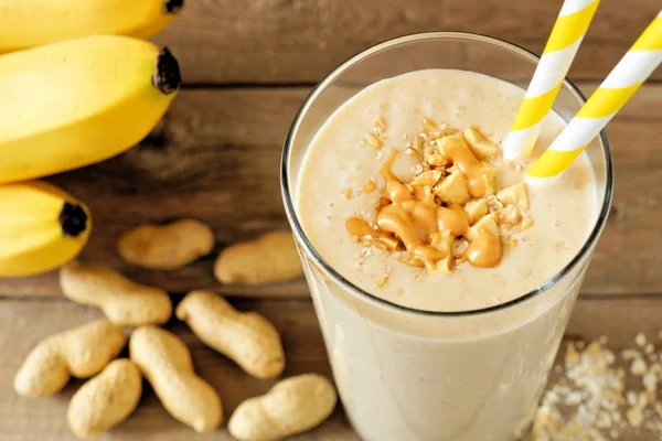 Smoothie de aveia de banana manteiga de amendoim na mesa de madeira com ingredientes — Fotografia de Stock