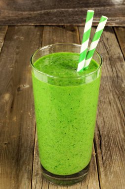 Bir cam çubuk rustik ahşap arka plan üzerinde ile yeşil smoothie