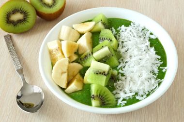 Muz, taze kivi ve Hindistan cevizi tablo sahne ile yeşil smoothie kase