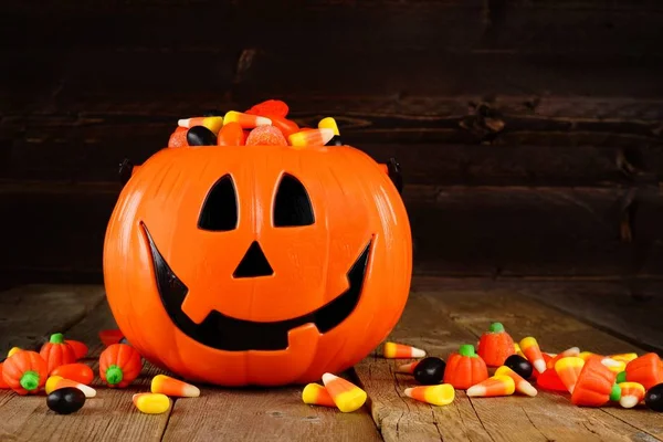 Halloween Jack o Lantern candy holder with scattered candy on wood — Stock Photo, Image